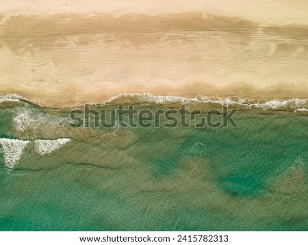 The view from above is a mesmerizing seascape with waves, a sandy beach and turquoise water. A beautiful picture from a drone, from a bird's-eye view. Copy space, nature background, Mockup.