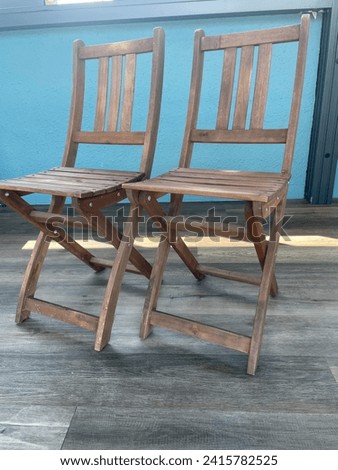 Close up photo view of 2 wooden foldable chairs side by side together as a pair twin double furniture in wood to sit on it or unfold