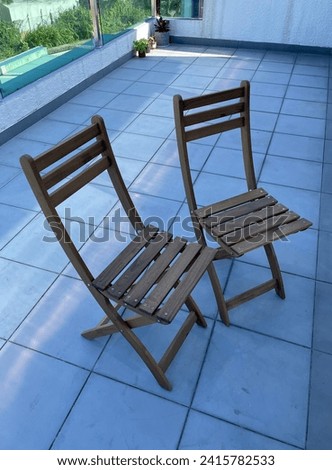 Close up photo view of 2 wooden foldable chairs side by side together as a pair twin double furniture in wood to sit on it or unfold