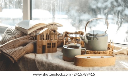 Cozy winter photo, stack of sweaters, book, tea and candle.