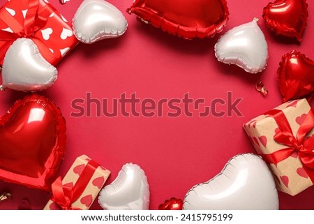 Frame made of heart shaped air balloons and gift boxes on red background. Valentine's Day celebration