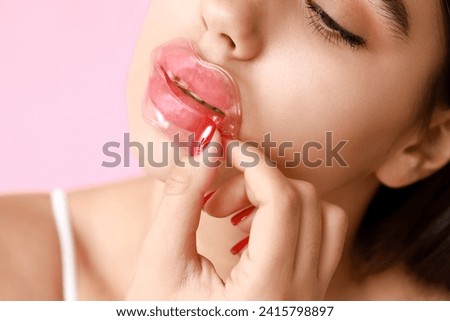 Beautiful young woman with lip mask on pink background, closeup Royalty-Free Stock Photo #2415798897