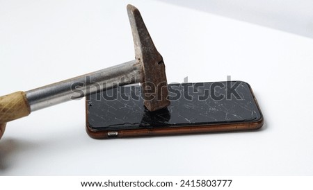 photo of smartphone with hammer on top of broken touchscreen display on white background