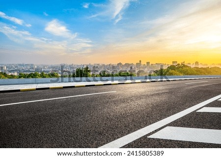 Asphalt road and city skyline with modern buildings scenery at sunrise