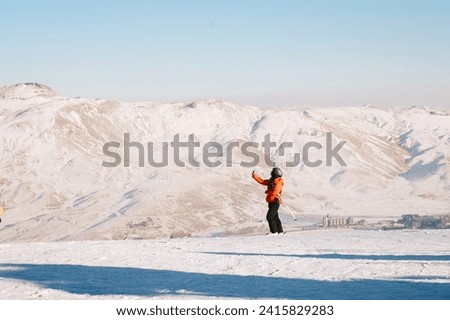 Woman taking picture using mobile phone while winter against the mountain