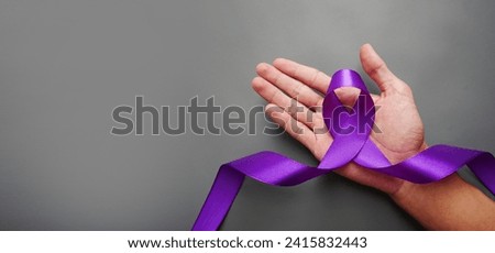 hands holding purple ribbon. World cancer day, lavender purple ribbon to support people living with cancer. Raise awareness of all types of cancer. Healthcare and medical concept.