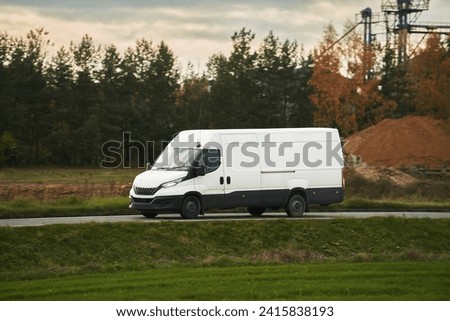 A mockup of a white van with an empty wrap for you to customize. A commercial vehicle for your delivery and transport service. Isolated small white truck on the road. Royalty-Free Stock Photo #2415838193
