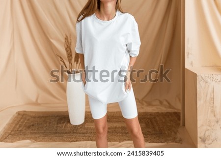 White woman clothing mockup. A girl in a modern minimalist setting wears a stylish white outfit showcasing comfort and elegance.  Oversized white shirt no logo.