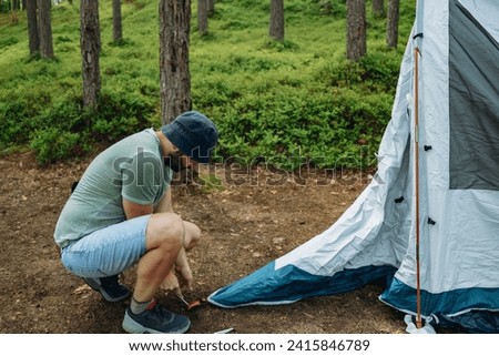 caucasian man putting up a tent in pine forest. Family camping concept. High quality photo