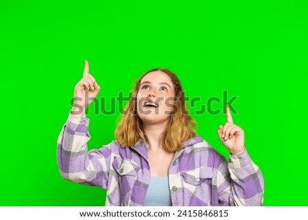 Young woman showing thumbs up and pointing empty place over head, advertising area for commercial text, copy space for goods promotion advertisement. Girl isolated on chroma key background. Lifestyles