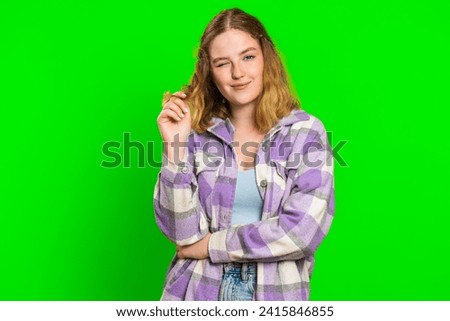 Smiling playful happy young caucasian woman blinking eye, looking at camera with smile, winking, flirting, expressing optimism, good news. Charming redhead girl isolated on green chroma key background