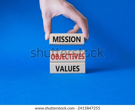 Mission Objectives Values symbol. Concept words Mission Objectives Values on wooden blocks. Beautiful blue background. Businessman hand. Business and Mission Objectives Values concept. Copy space