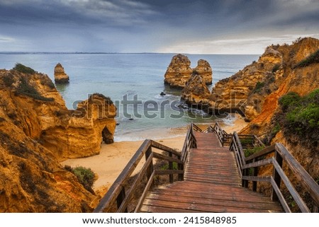 Algarve coast in Lagos, Portugal, Praia do Camilo with wooden stairs to the beach at the Atlantic Ocean. Royalty-Free Stock Photo #2415848985