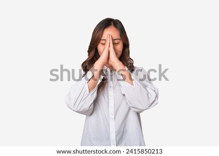 A young chinese woman holding hands in pray near mouth, feels confident.
