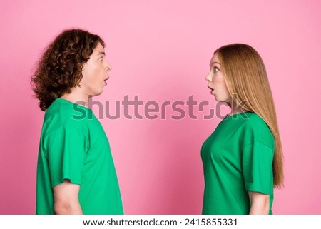 Side photo of two teeenagers look impressed each other when realized they wear accidentaly same t shirt isolated on pink color background