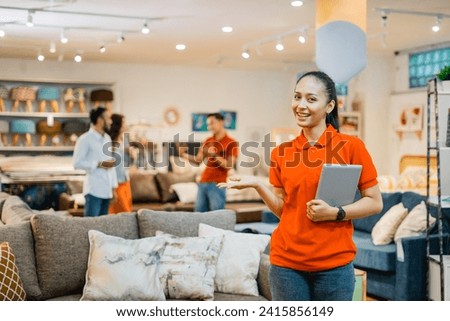 business woman with hand gestures presenting something holding a tablet standing against the background of buyer and shopkeeper in a furniture store
