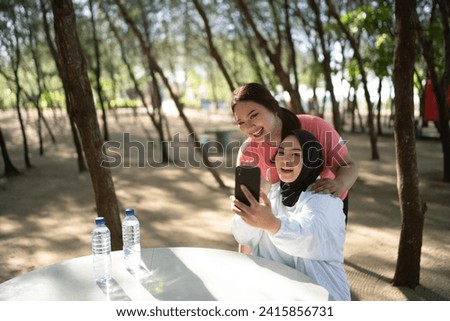 asian women in sportswear holding and taking picture with phone