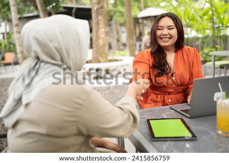 businesswoman handshake with her muslim colleague after reach an agreement about work