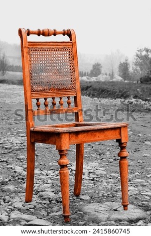 Orange object and black and white background, old colored wooden chair in landscape, color photography