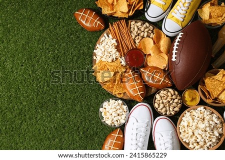 A bowl with various beer snacks and a rugby ball on the grass Royalty-Free Stock Photo #2415865229