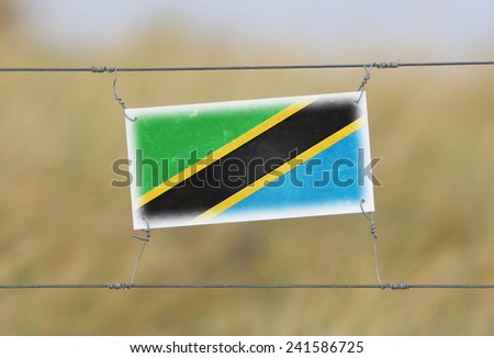 Border fence - Old plastic sign with a flag - Tanzania