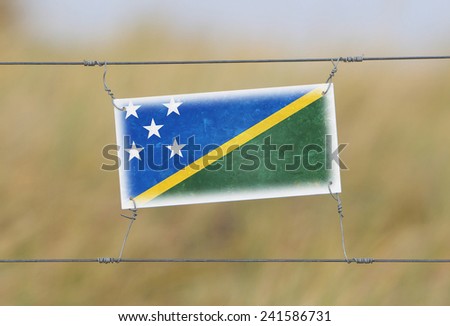 Border fence - Old plastic sign with a flag - Solomon Islands