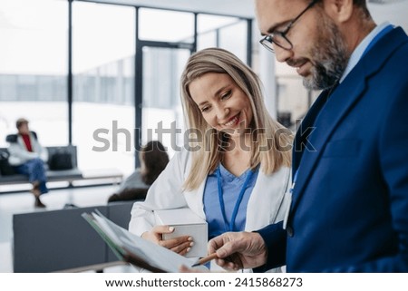 Pharmaceutical sales representative talking with doctor in medical building. Female doctor talking with hospital director, manager in private clinic. Royalty-Free Stock Photo #2415868273
