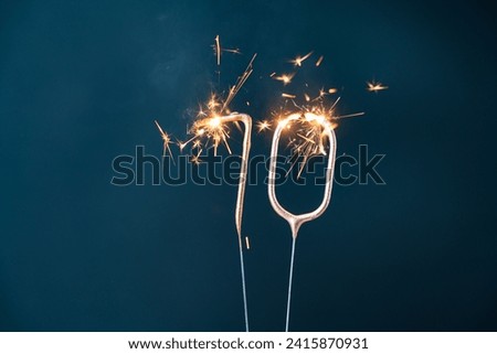 70 years celebration festive background made with Bengal fires in the form of number Seventy. Royalty-Free Stock Photo #2415870931