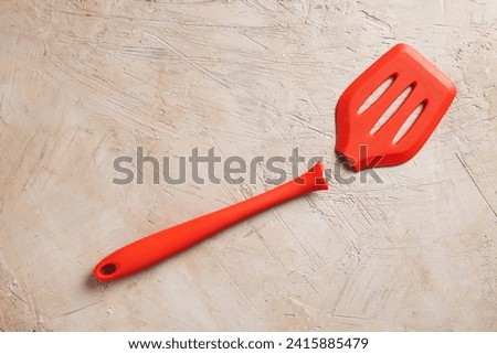 a broken red spatula on a textured background Royalty-Free Stock Photo #2415885479
