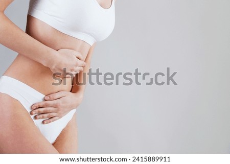 Cropped shot of woman touching her stomach due to the abdominal pain. Unrecognizable female experiencing stomachache. Close up, copy space, background.