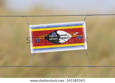 Border fence - Old plastic sign with a flag - Swaziland