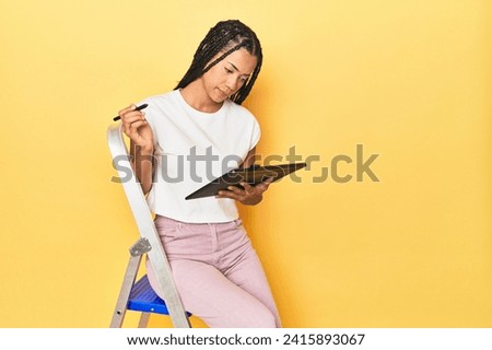 Young Indonesian woman using graphic tablet on yellow studio backdrop
