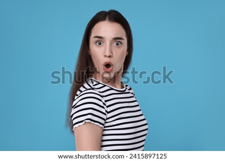 Portrait of surprised woman on light blue background