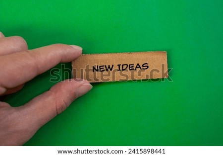 New ideas lettering on ripped cardboard paper piece with green background. Conceptual business photo. Top view, copy space for text.