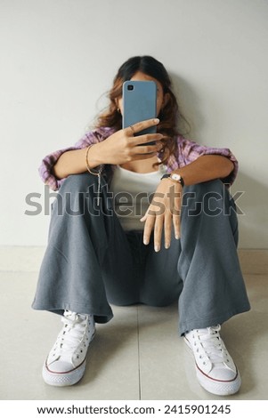 Teenage girl in wide pants, cotton tank top and plaid shirt taking mirror selfie Royalty-Free Stock Photo #2415901245