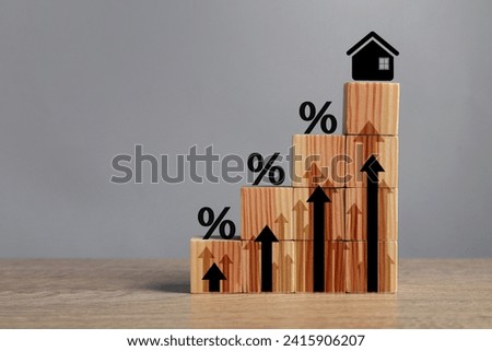 Mortgage rate rising illustrated by upward arrows, percent signs, house icon and cubes on wooden table, space for text