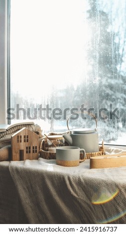Cozy winter home interior, candle, tea and teapot on the windowsill.