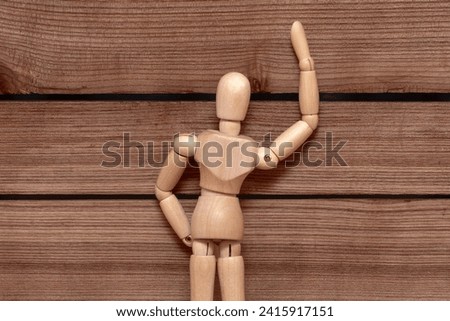 A wooden mvneken peeps into the sheel of a wooden fence, voyeurism. High quality photo Royalty-Free Stock Photo #2415917151