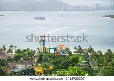 Nha Trang Bay with colorful water park, cruise, watercraft on the beach and row of downtown skylines high-rise apartment, mountain range in background, tropical family aqua park, lush trees. Vietnam