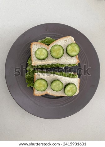 Interior photo view of a delicious yummy tasty healthy Ham Salad Sandwich with fresh Cucumber on top for breakfast, snack, lunch or diner view from top on a kitchen table on a grey gray plate