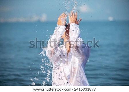 A woman in a white wet shirt is bathing and doused with sea water. Royalty-Free Stock Photo #2415931899