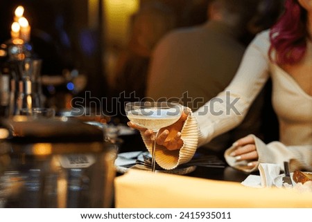 A girl takes a glass of sparkling champagne at a bar