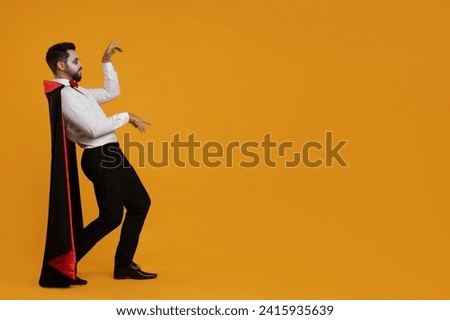 Man in scary vampire costume with fangs posing on orange background, space for text. Halloween celebration