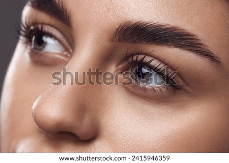 Close-up of a woman's eyes with well-defined eyebrows, long lashes, and smooth skin, highlighting meticulous grooming. Concept of mascara brand, lash volume and eye enhancement. Ad