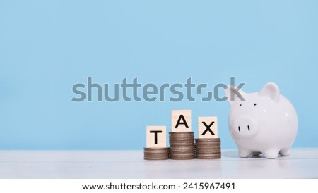 Piggy bank and wooden blocks with the word TAX on stack of coins. The concept about saving money and manage time to paying tax
