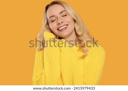 Happy woman in stylish warm sweater on orange background
