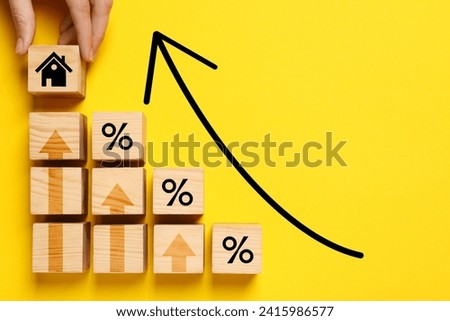 Mortgage rate rising illustrated by upward arrows. Woman putting wooden cube with house icon near other ones on yellow background, top view