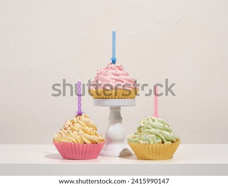Image of cheerful holiday. Colorful cupcake with birthday candles and whipped cream.