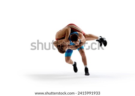Two strong and skilled wrestlers in blue and red wrestling uniform wrestling in motion against white studio background. Concept of fair wrestling, championship, win competition. Ad