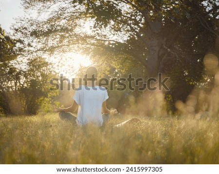 Young asian woman doing meditation in morning or evening at park, healthy woman relaxing and practicing yoga at city park. Mindfulness, destress, Healthy habits and balance concept Royalty-Free Stock Photo #2415997305